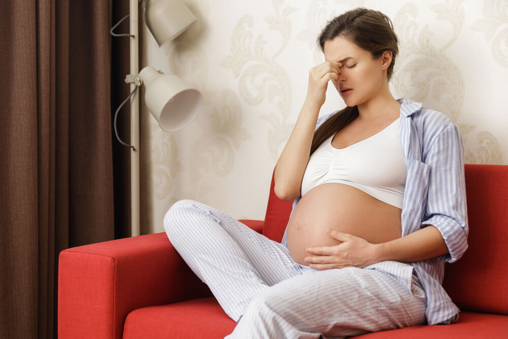 Young and pregnant woman at home feels sick with eye twitching