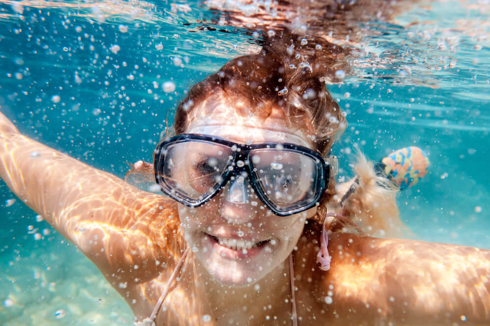 Young woman swimming underwater in blue ocean